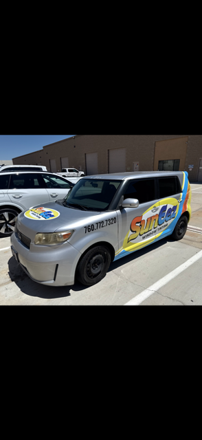 Silver compact car with colorful event decals parked in a sunny lot