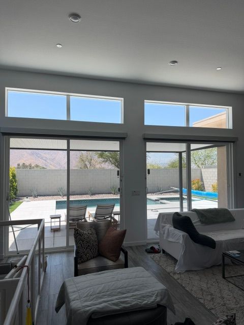 Bright living room with large windows overlooking a backyard pool and patio.
