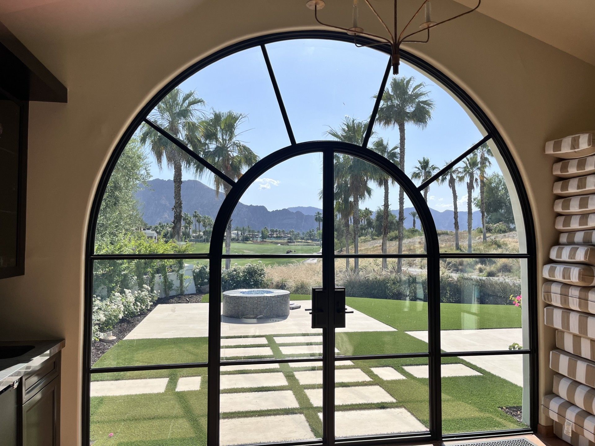 A view of a lush green field through a large arched window.