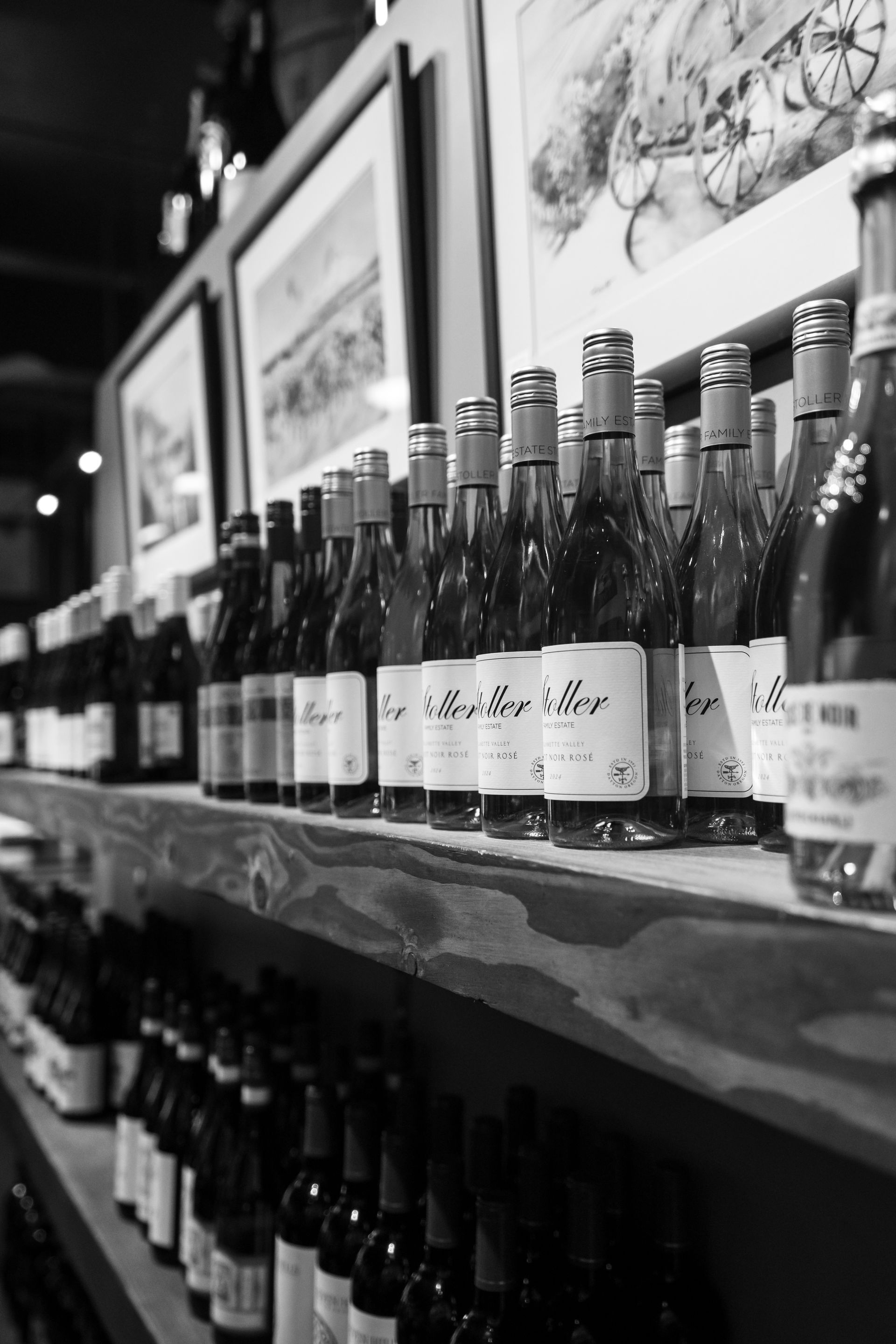 Rows of wine bottles on wooden shelves, black and white photograph.