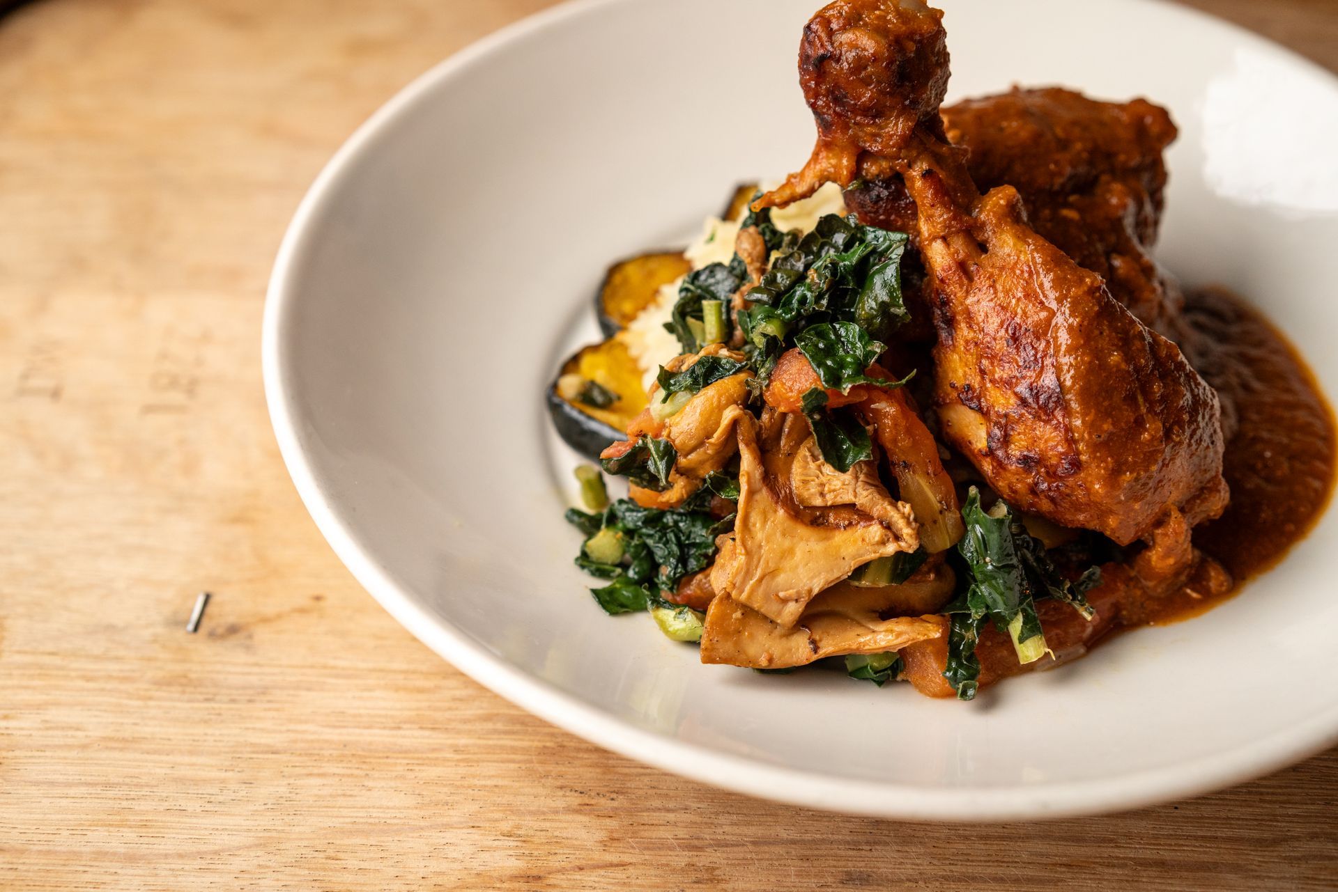 Plate of food, chicken with sauce, vegetables, and mushrooms.