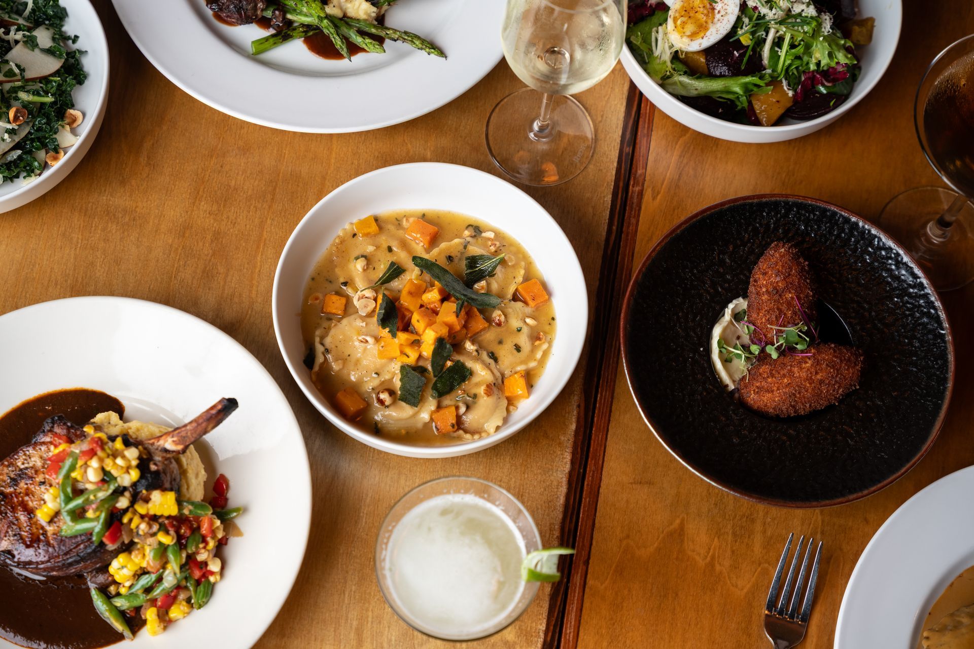 A table filled with various dishes, soup, salad, meat, and appetizers.