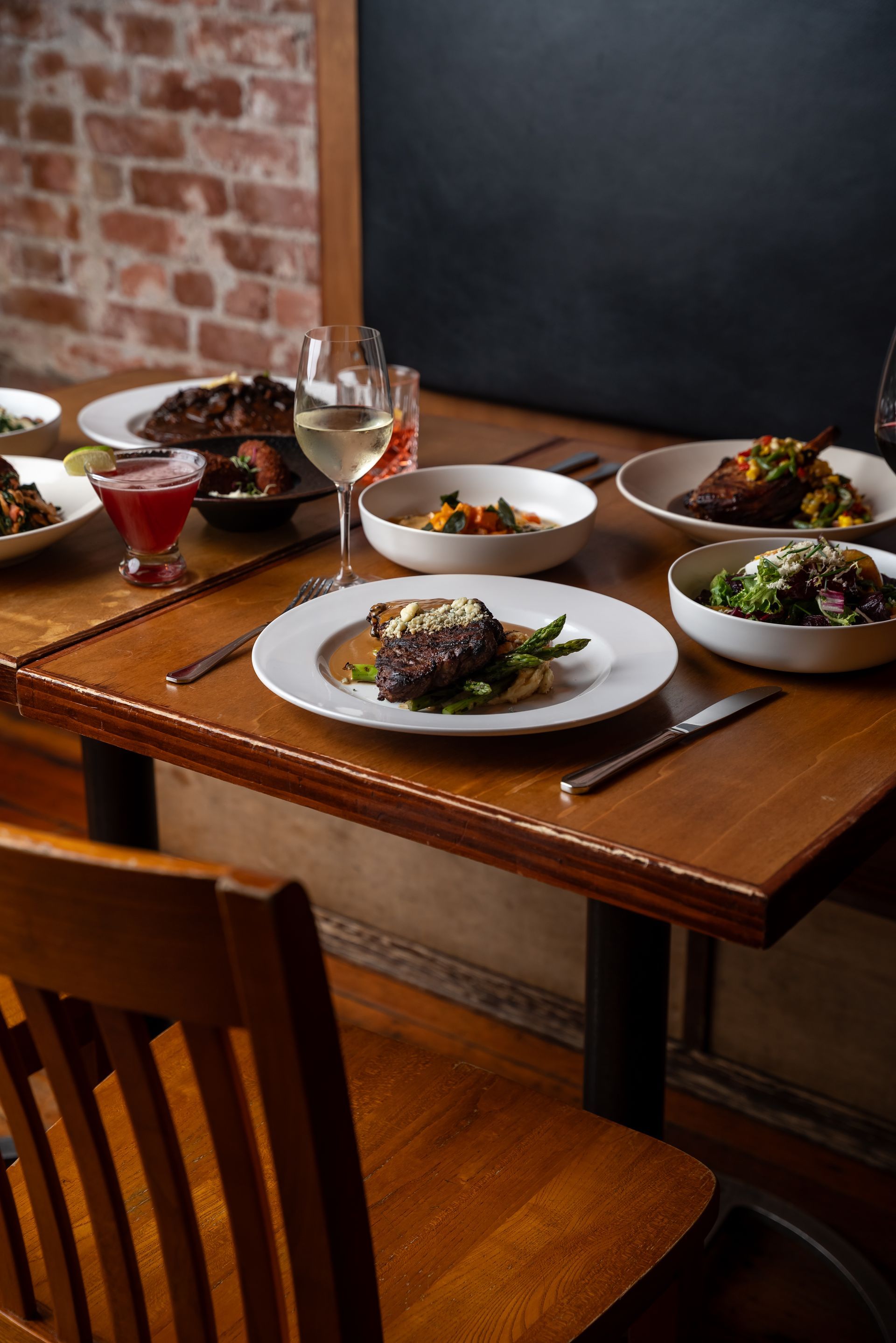 Wooden table set with various dishes and drinks in a restaurant.