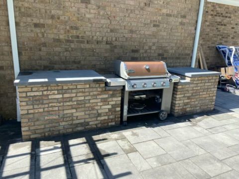 Brick outdoor grill station with stainless-steel barbecue and side counters on a patio