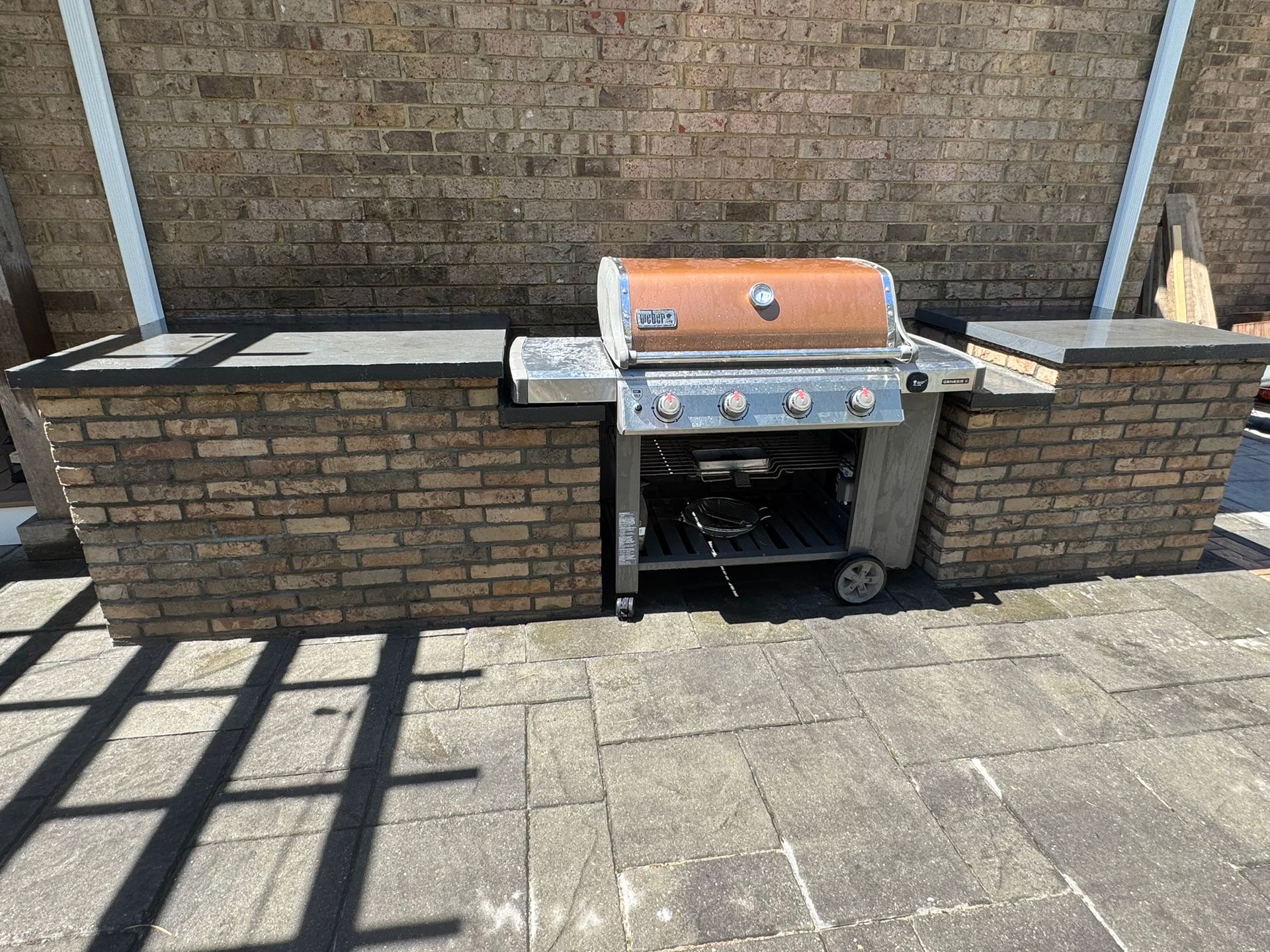 Brick patio with a silver gas grill built into a brick outdoor cooking area.