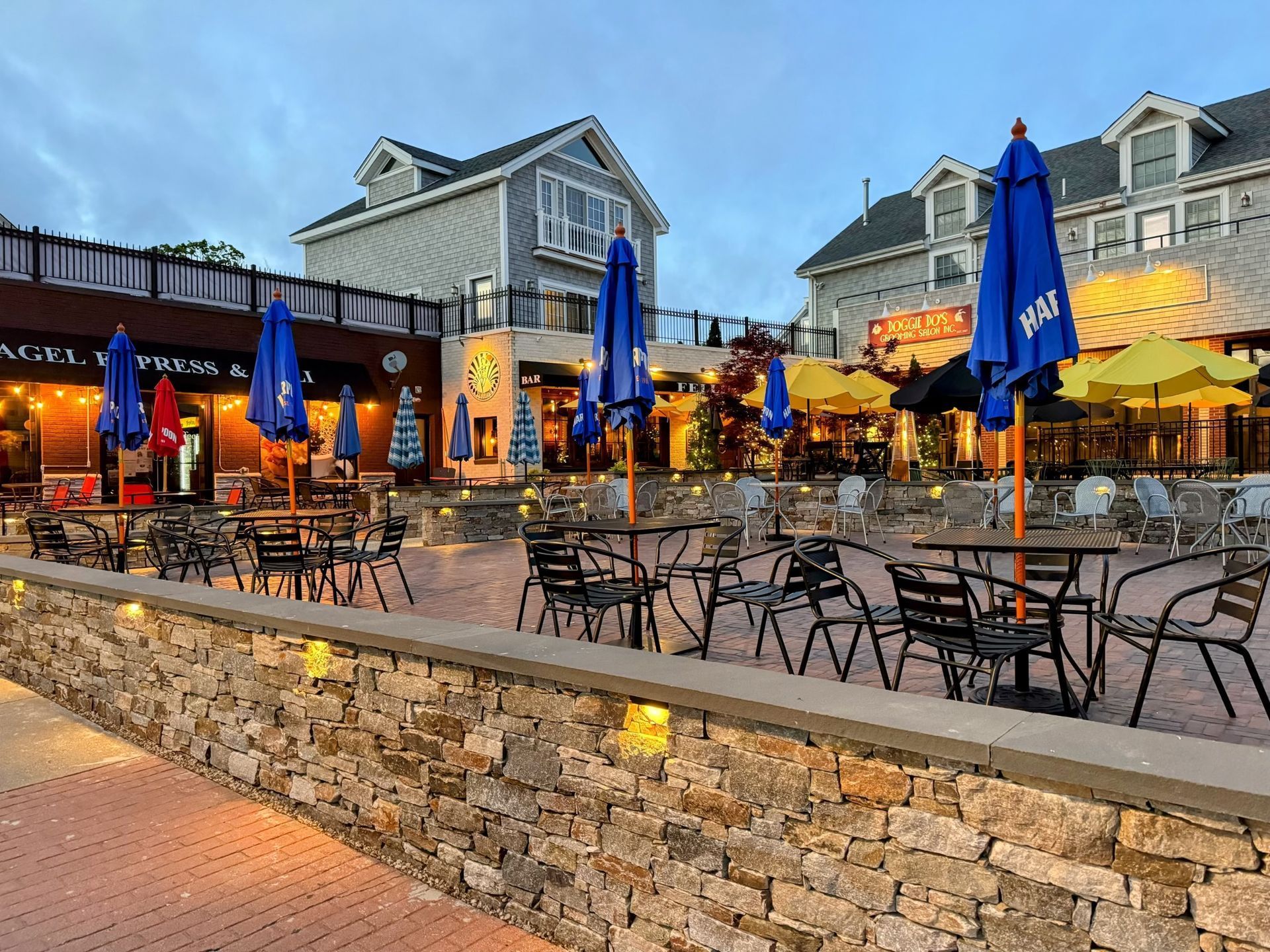 a patio area with tables chairs and umbrellas in front of a building