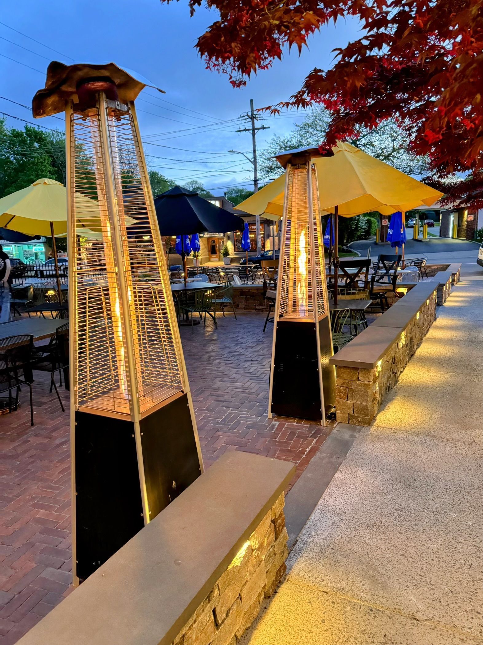 a patio with umbrellas and heaters on the sidewalk