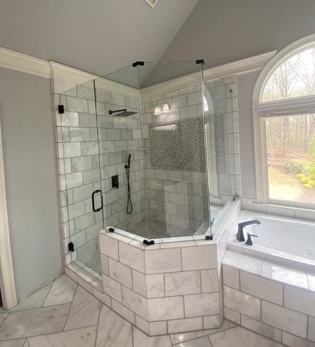 A bathroom with a tub , shower , and window.