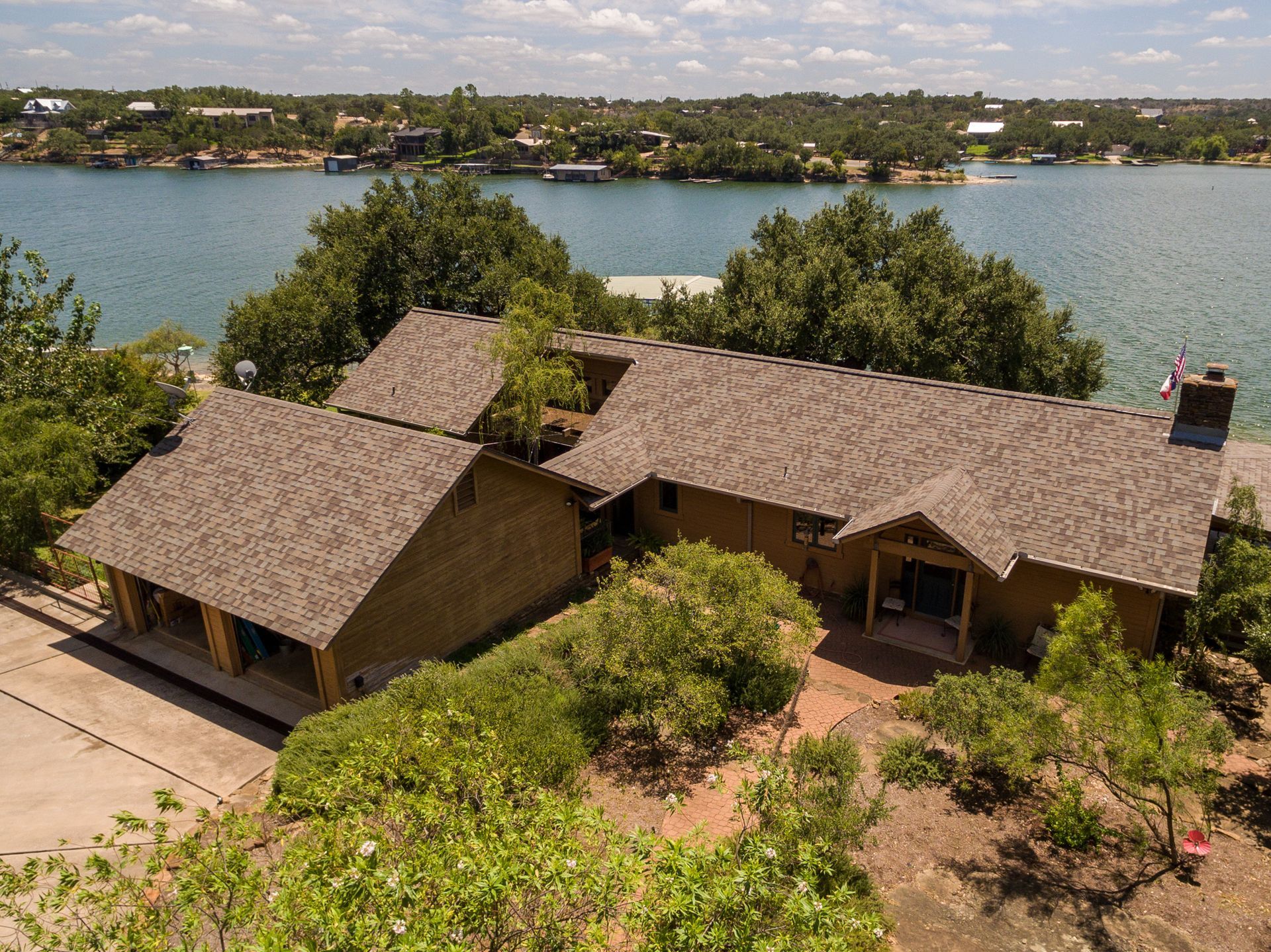 Two thatched-roof cottages beside a lake, surrounded by trees and greenery