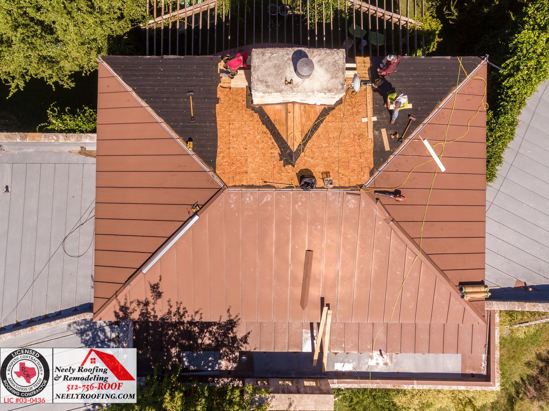 Aerial view of a rooftop with workers and safety equipment around a central hatch.