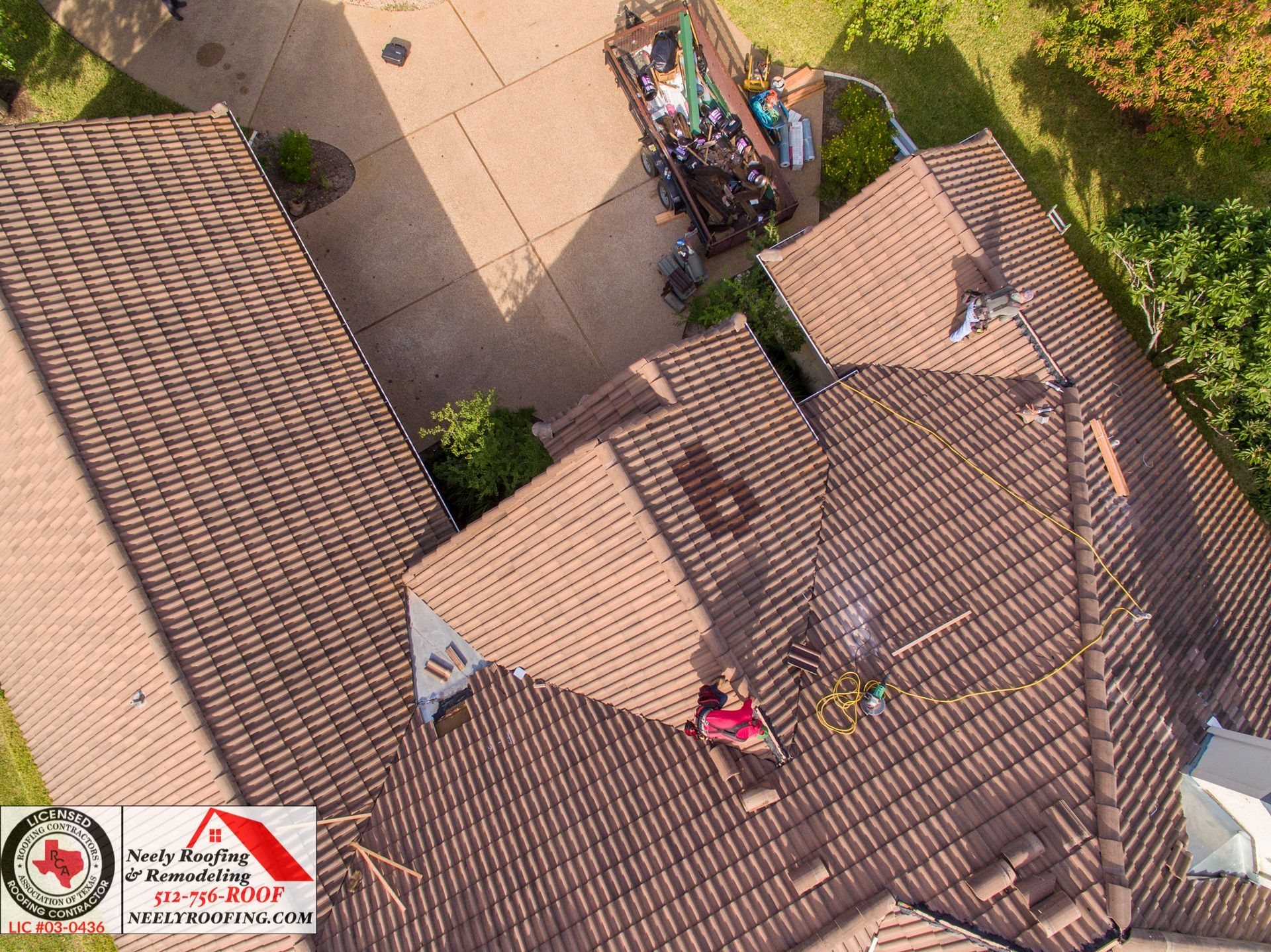 Aerial view of rooftops and a courtyard with a few people gathered near a walkway.