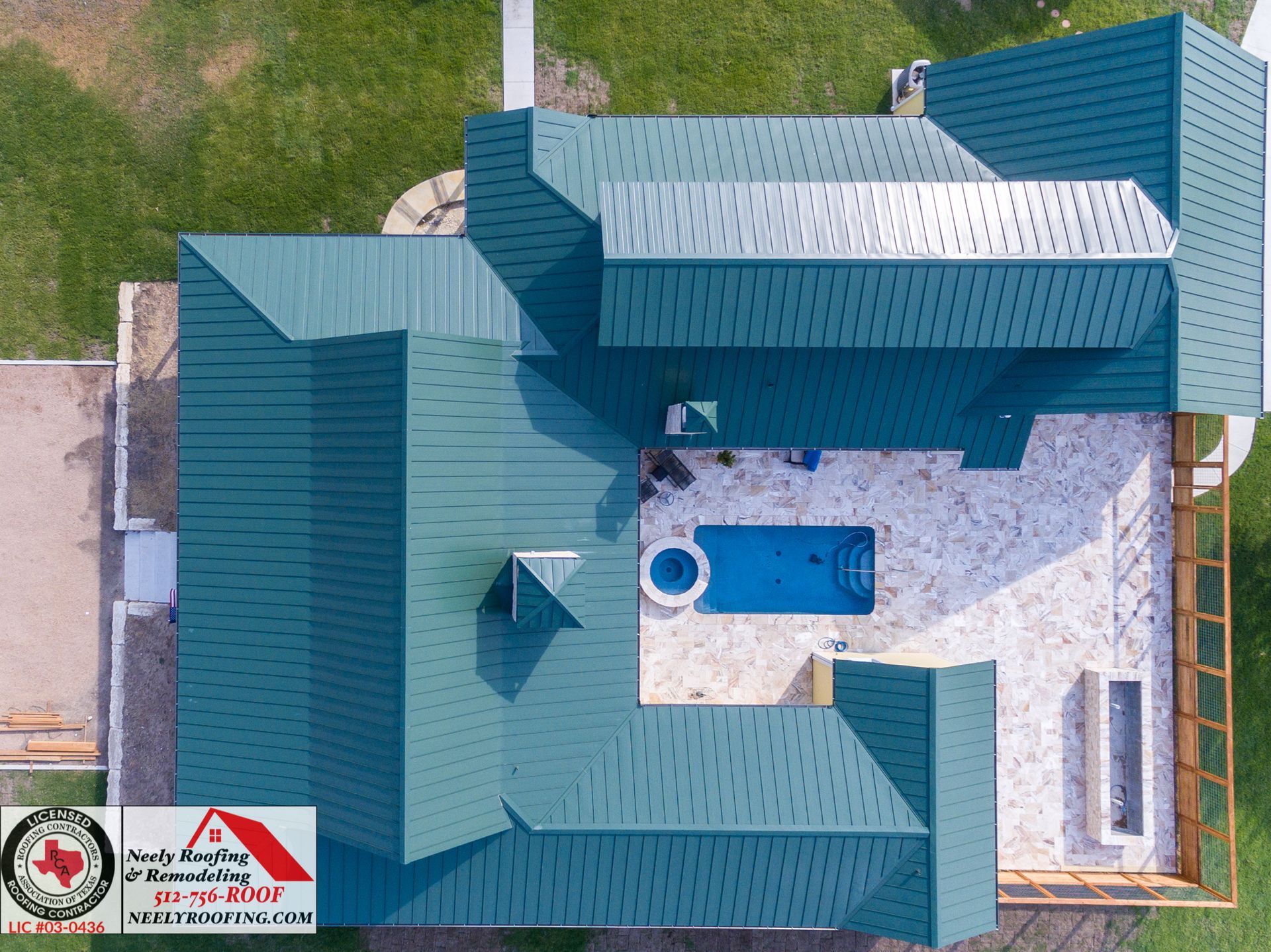 Aerial view of a teal-roofed house with a small blue pool and paved courtyard.
