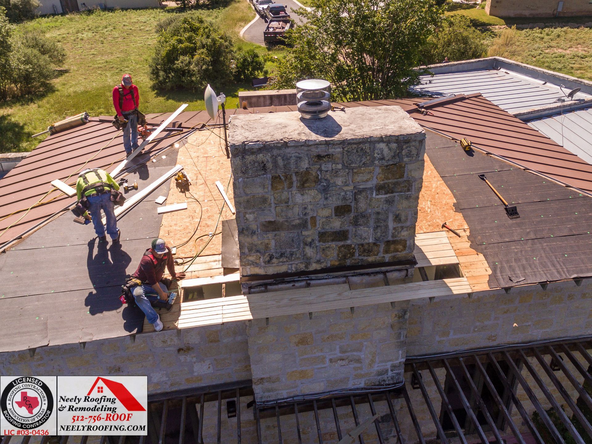 Roofers repairing a chimney on a shingled roof, with tools and materials spread across the rooftop.