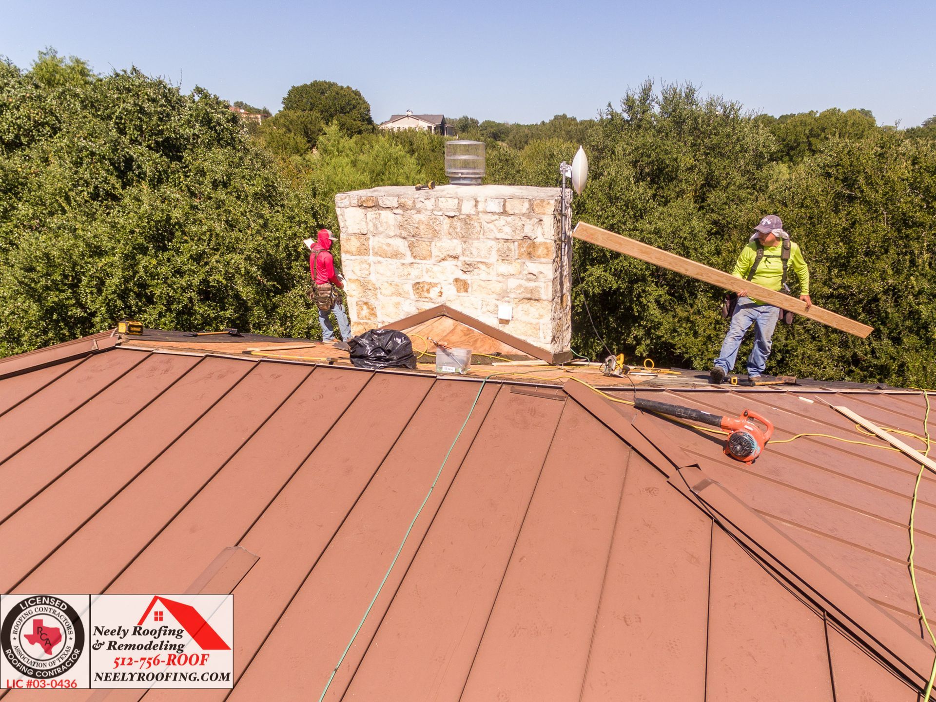 Two workers on a copper roof repair a stone chimney, with a long plank and tools nearby.