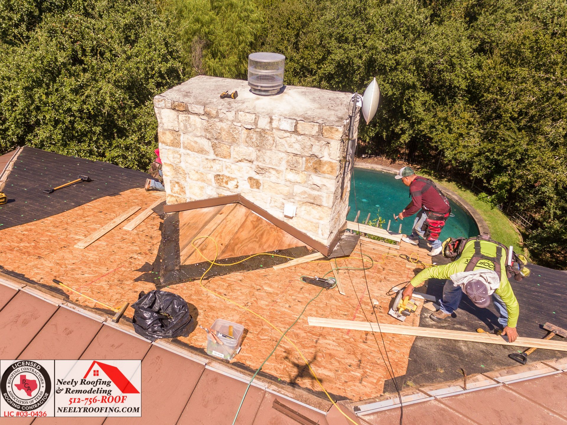 Damaged rooftop with torn shingles around a brick chimney and a worker inspecting repairs