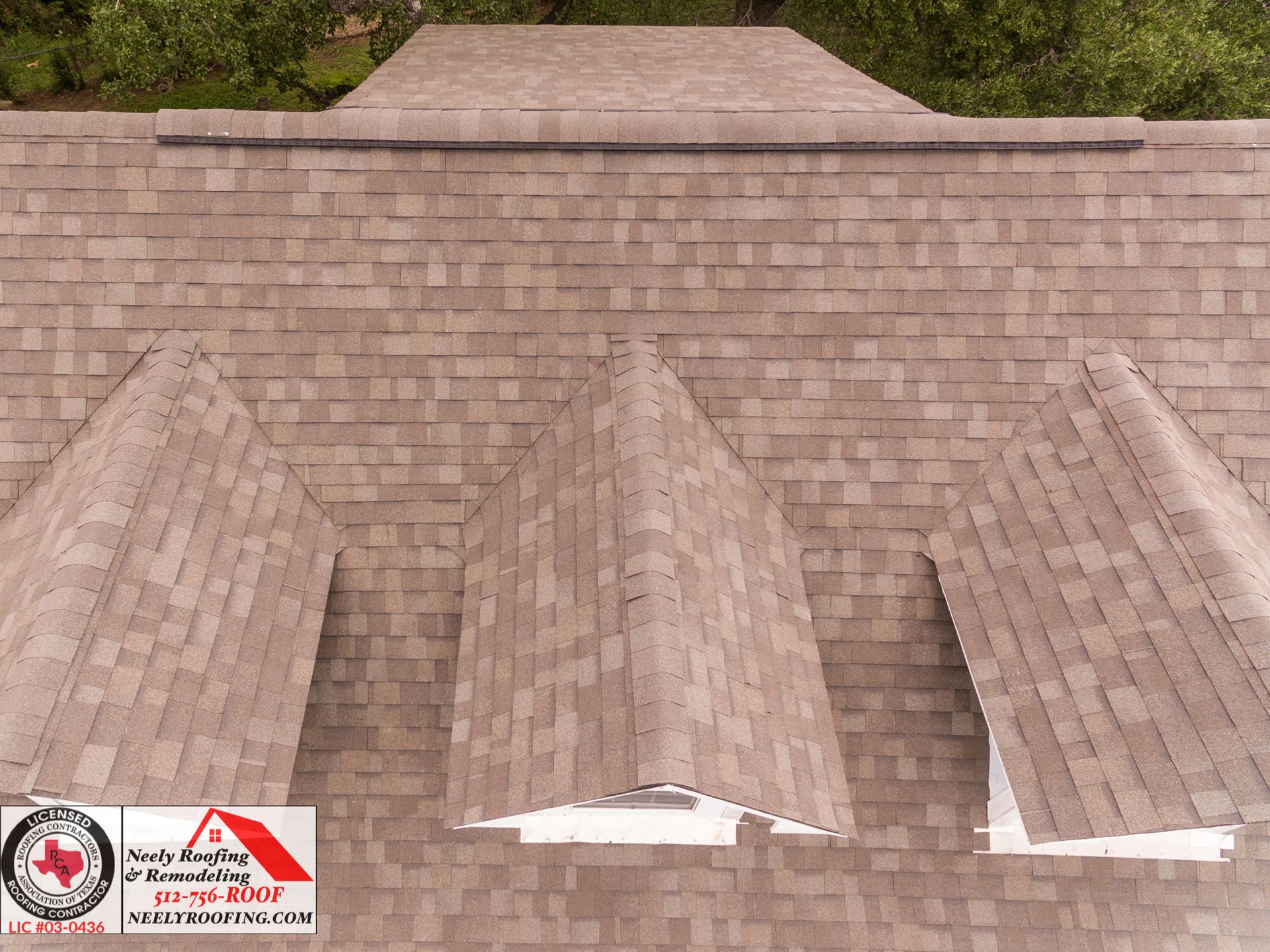 Rooftop with multiple skylights and brown shingles, with safety labels in the lower left corner