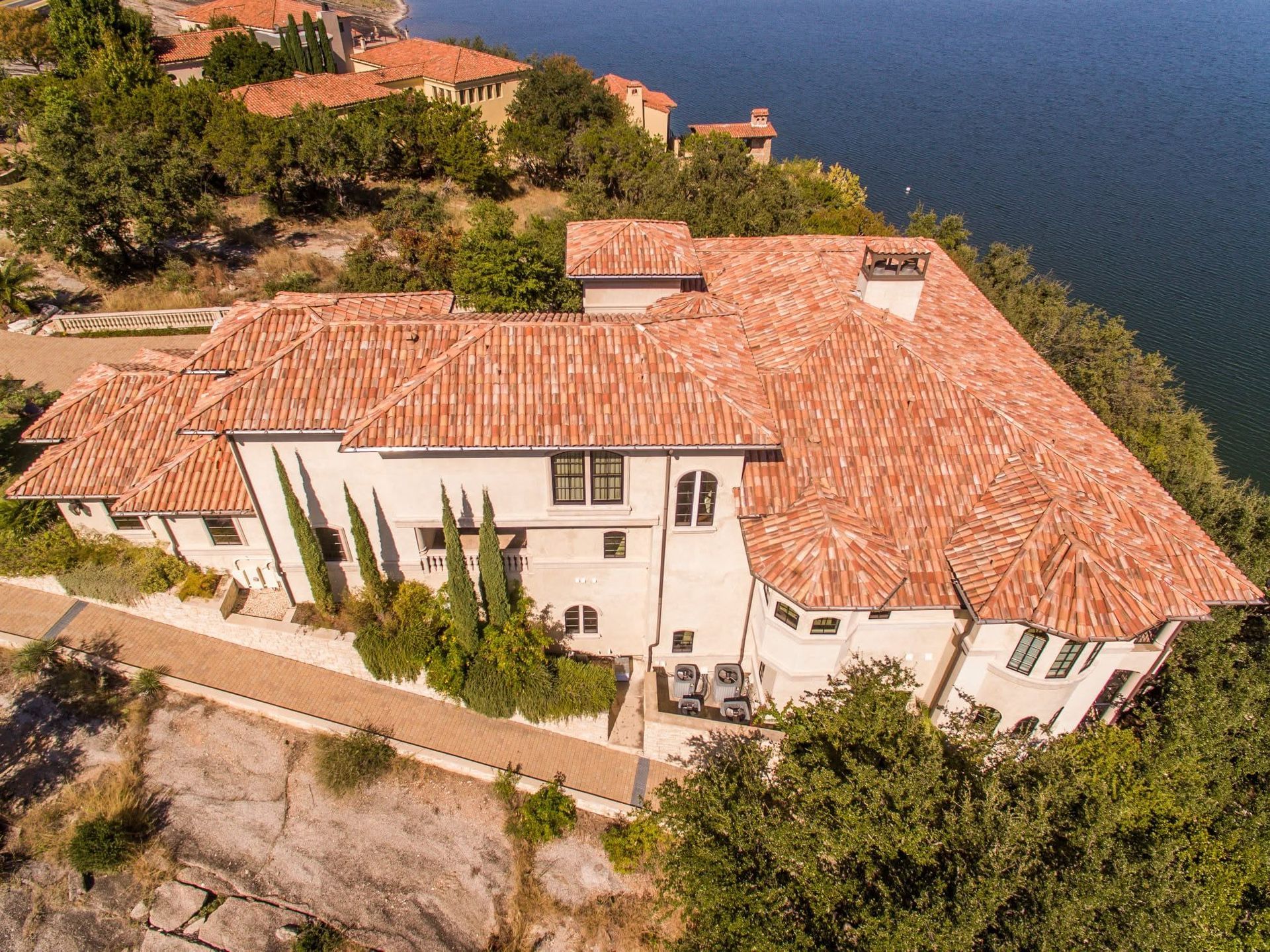 Cliffside white house with terracotta roof overlooking blue water and trees
