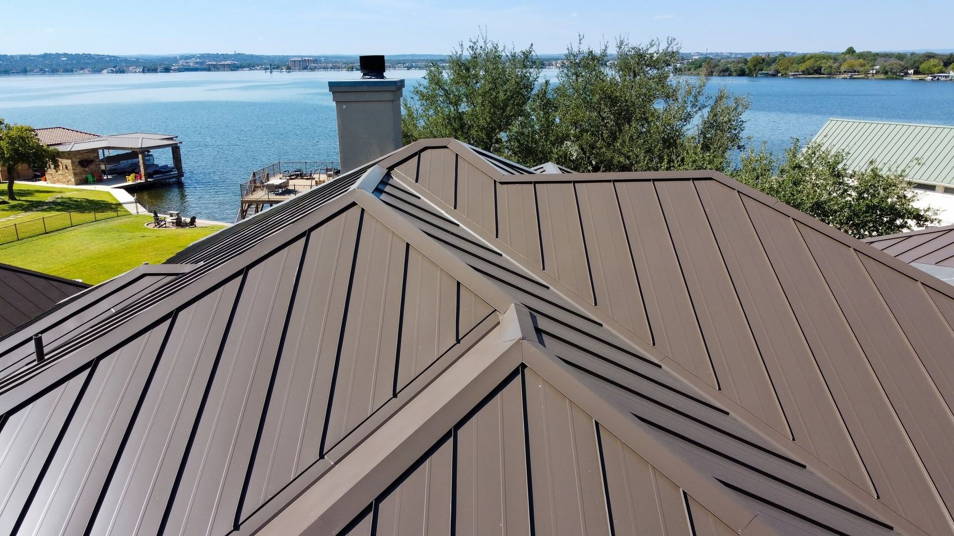 Brown metal roof with skylight overlooking a lake and distant shoreline