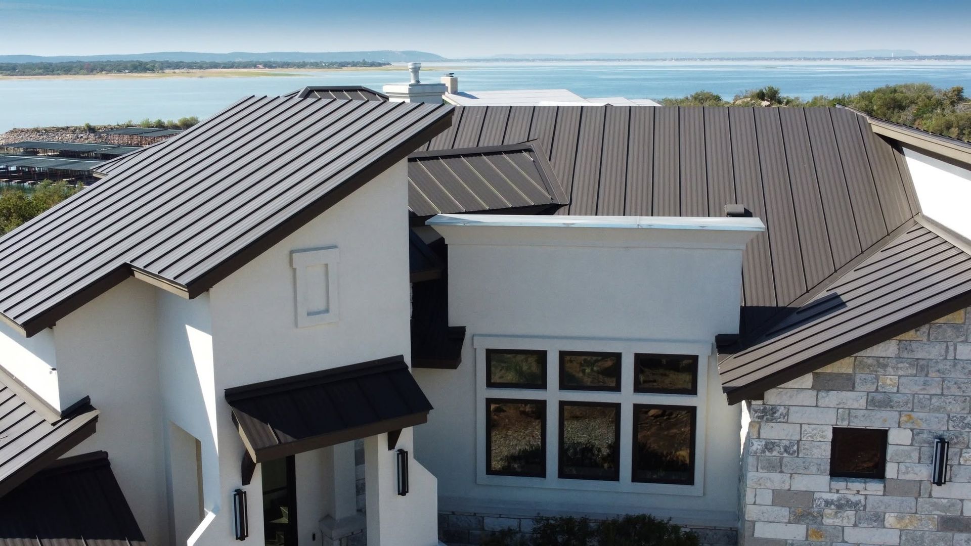 Modern house with white stucco walls, dark metal roof, and ocean view in the background