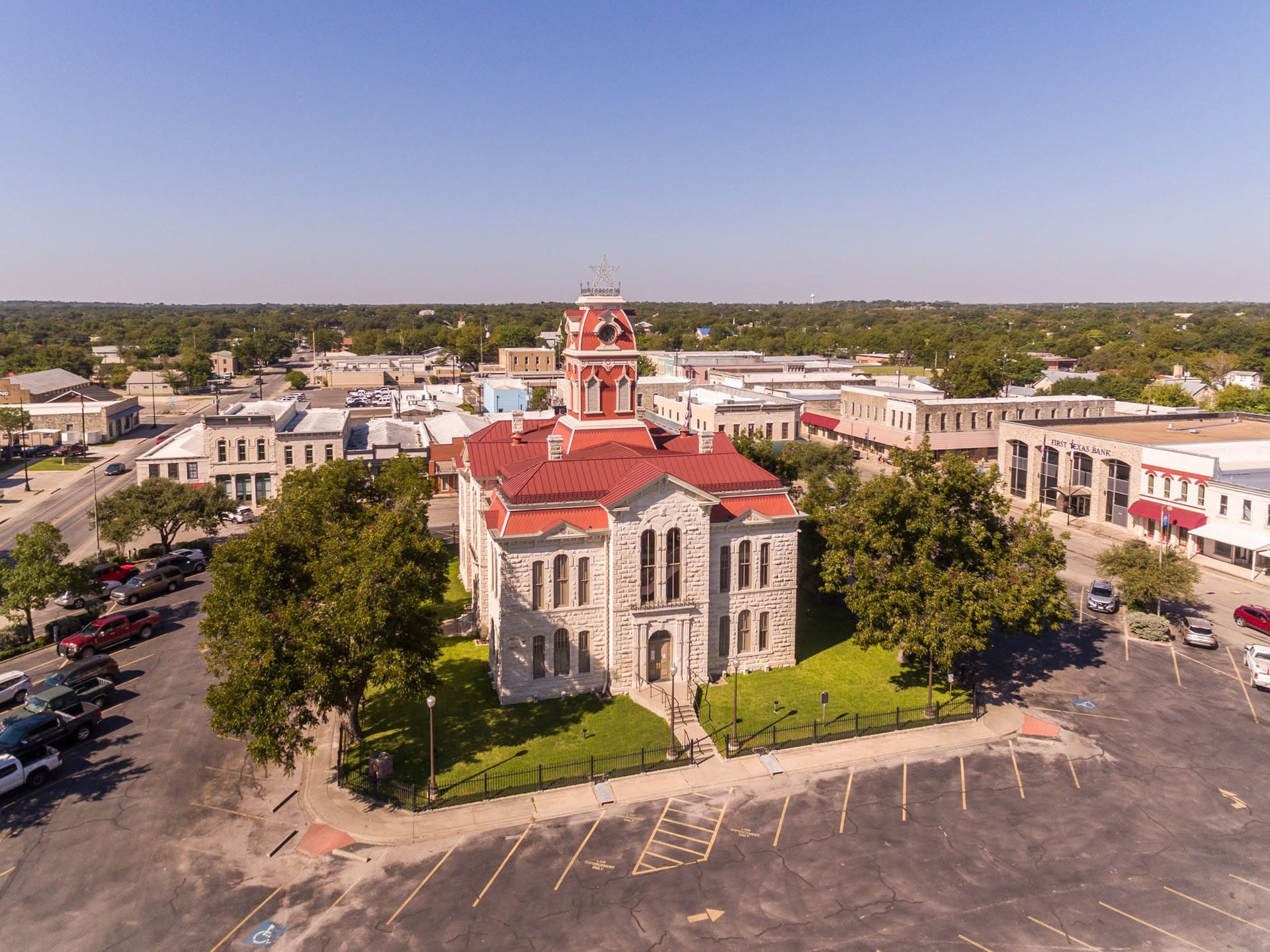 Aerial view of a historic stone church with a red roof in a town square.