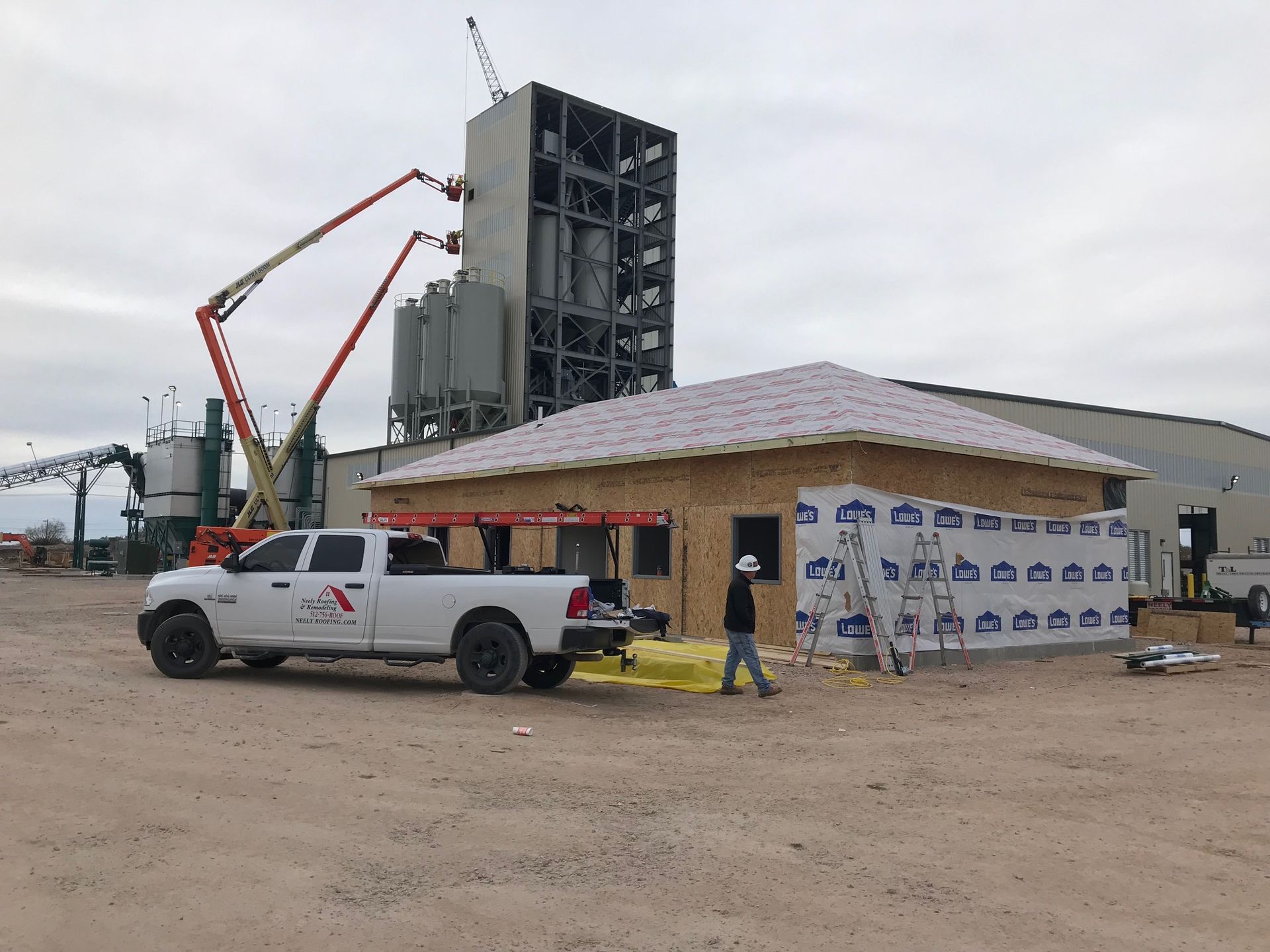 Construction site with a crane, white utility truck, and a small building under construction
