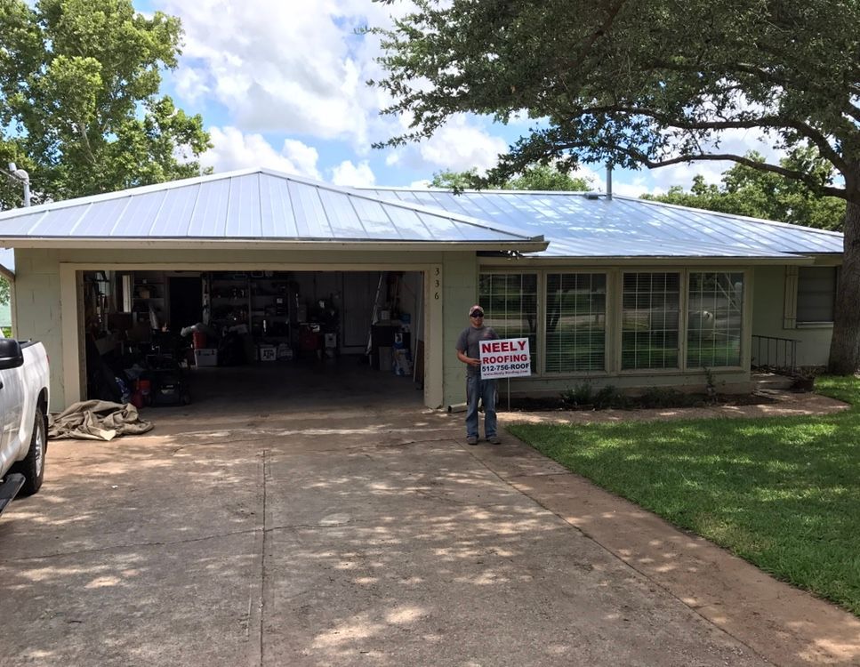 House with open garage and person holding a yard sign in the driveway
