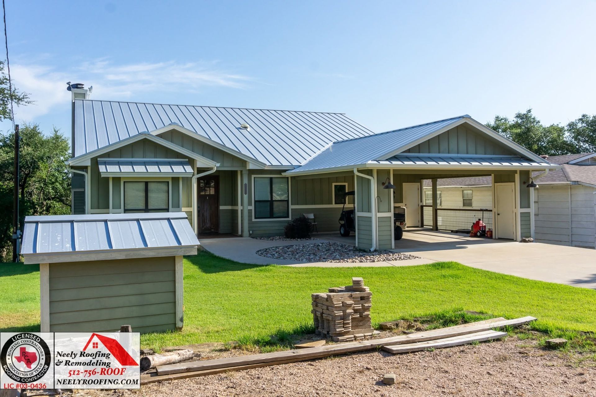 Single-story house with metal roof, front porch, garage, and green lawn under a clear sky