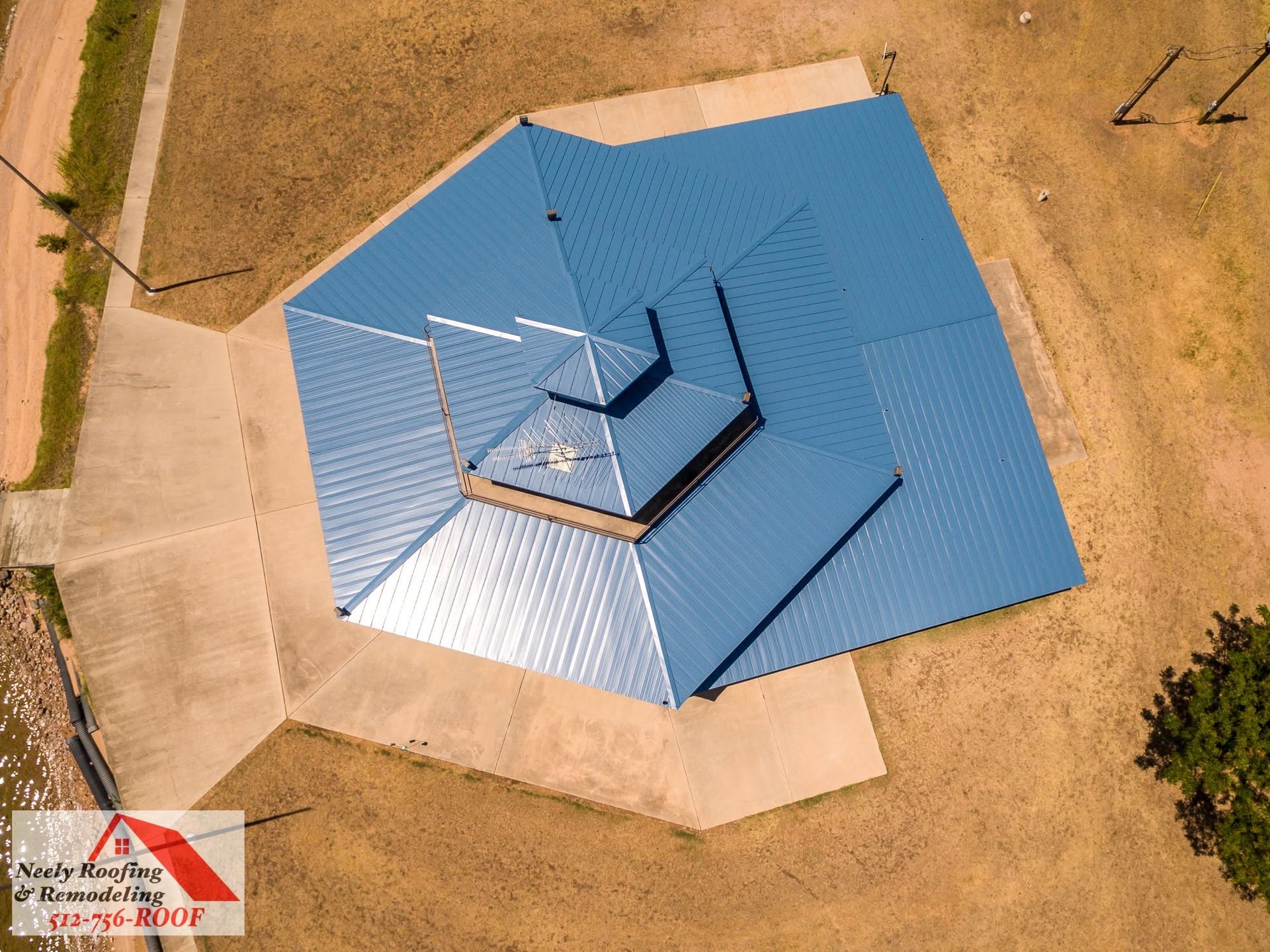 Aerial view of a blue metal roof on an octagonal building with a small central chimney.