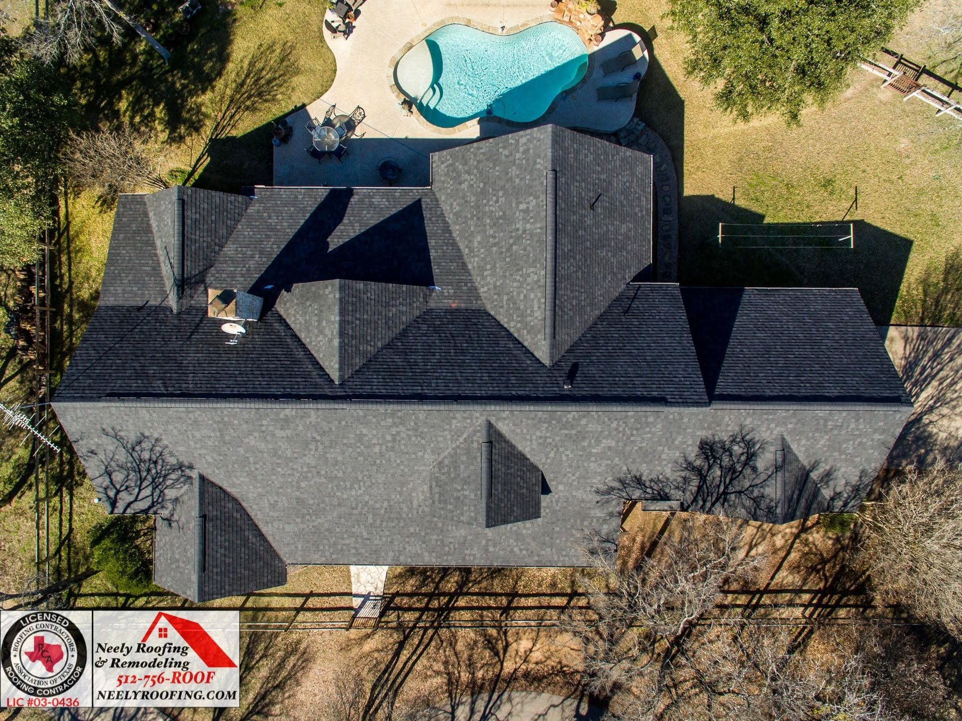 Aerial view of a house with a dark gray roof and a turquoise pool in the backyard.