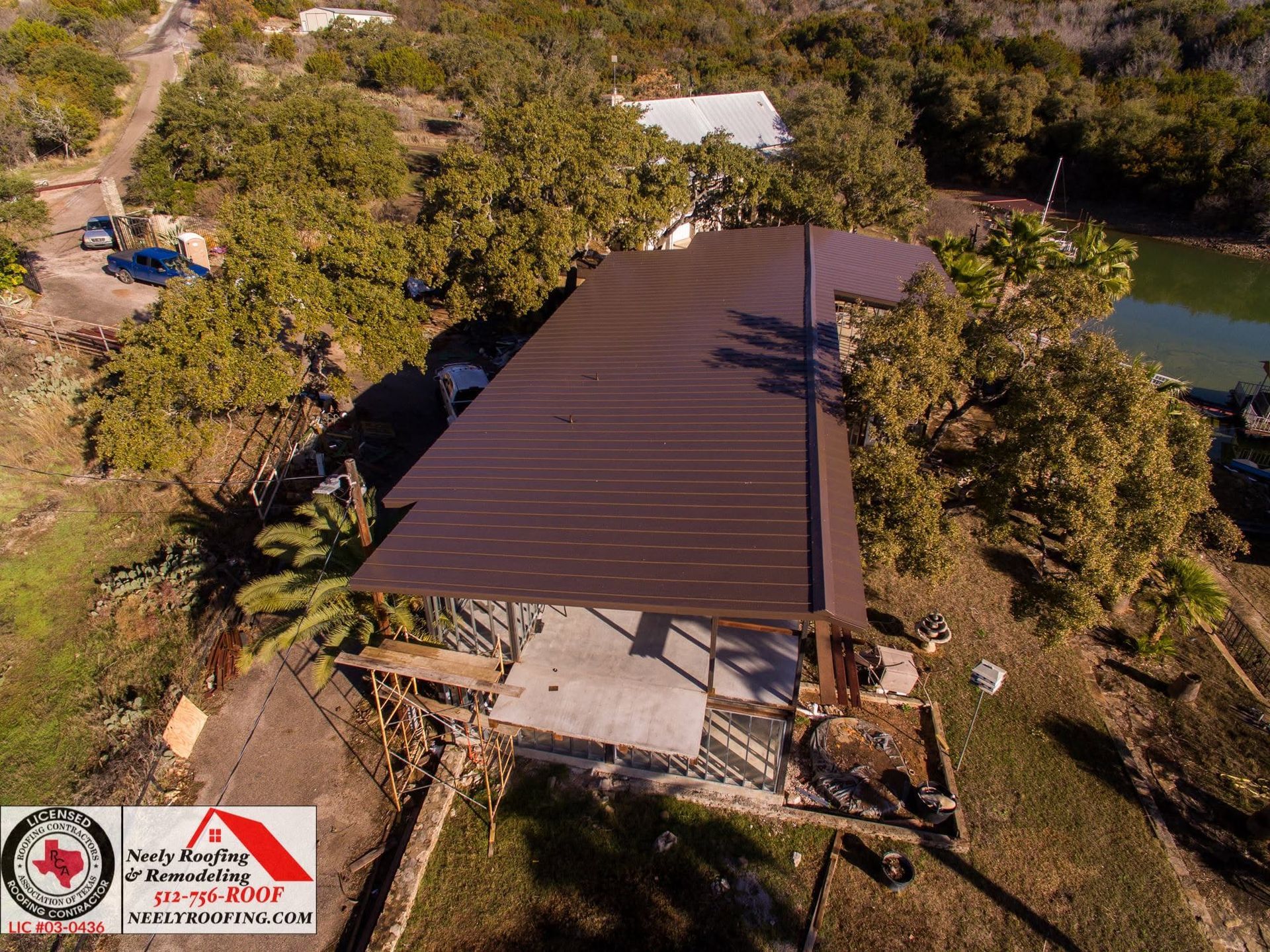 Aerial view of a damaged building with a collapsed roof and surrounding trees.