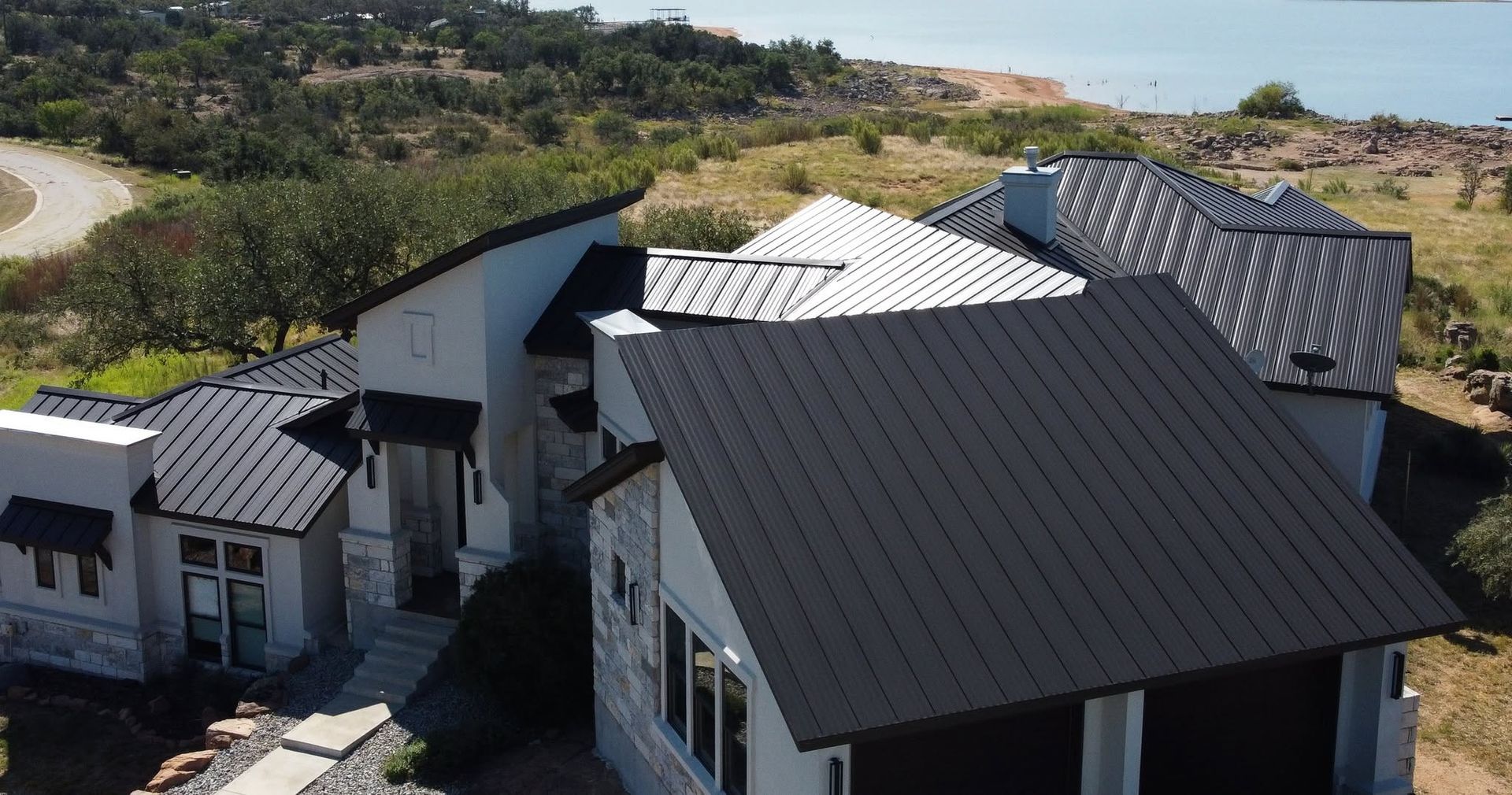 Modern house rooftops with dark metal and white panels in a hillside setting