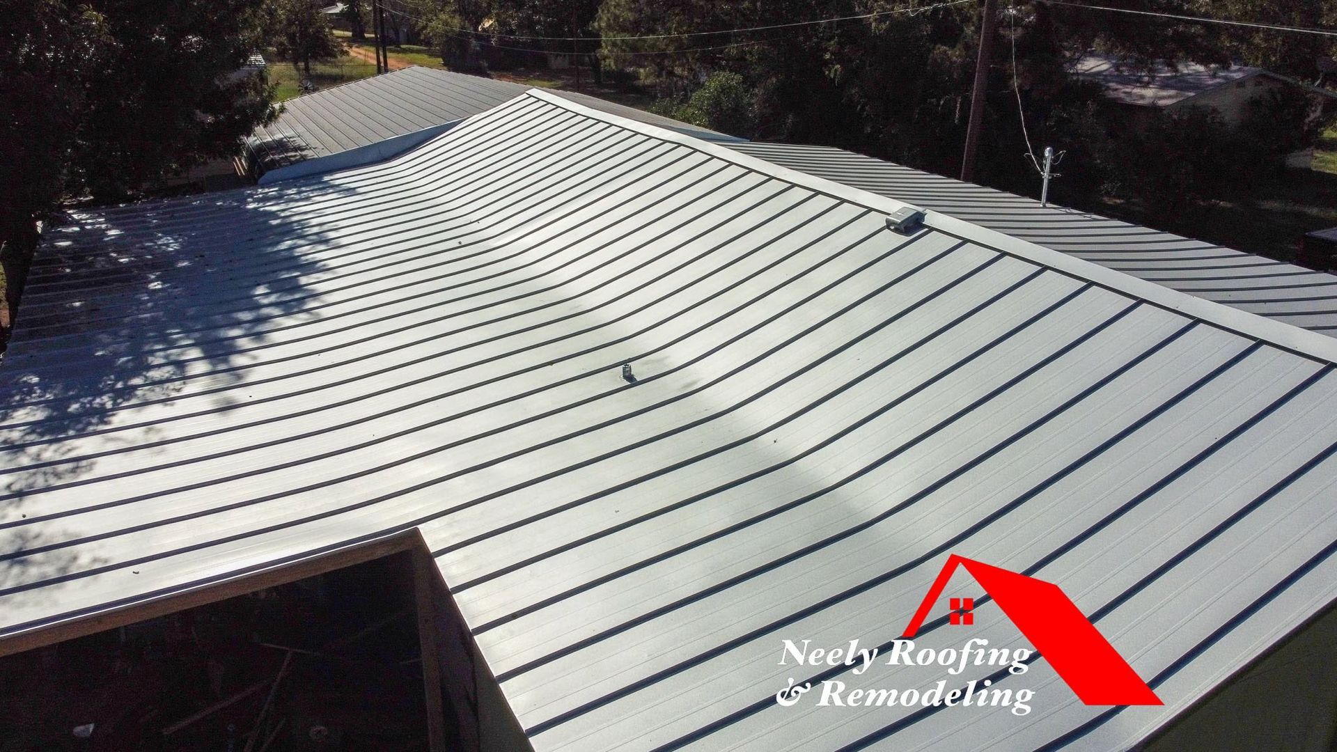 Metal roof with raised seams and a red arrow highlighting a roof vent near the lower edge.