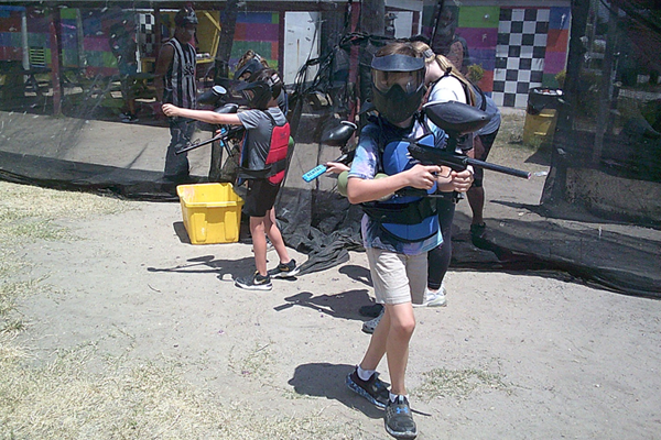 A group of children are playing paintball on a sunny day.