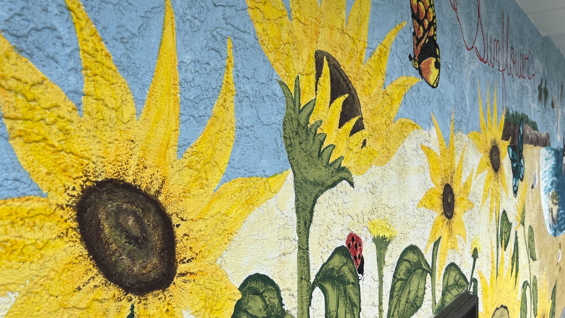 A painting of sunflowers and butterflies on a wall.