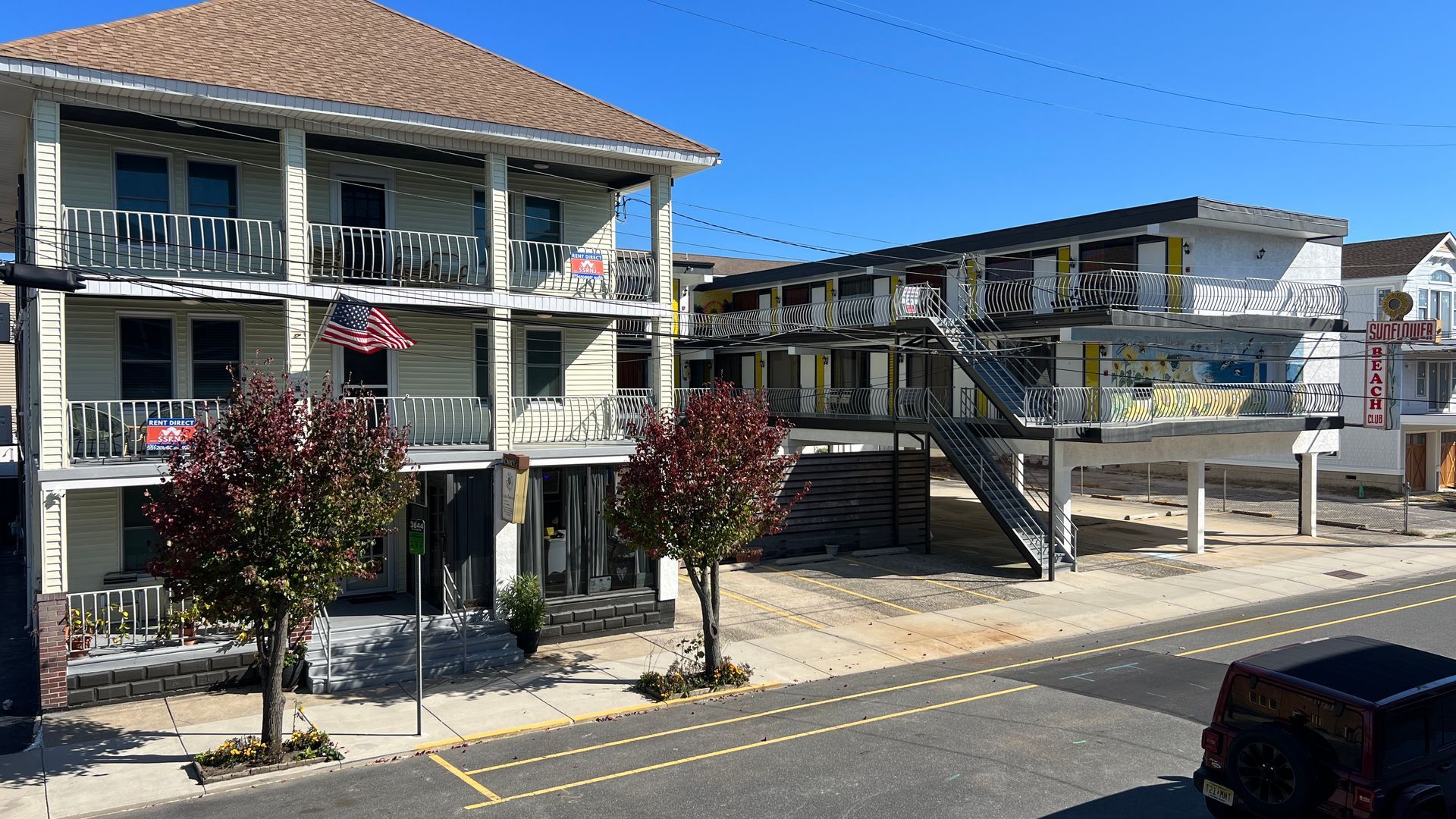 A large white building with stairs and balconies is sitting on the side of a road.