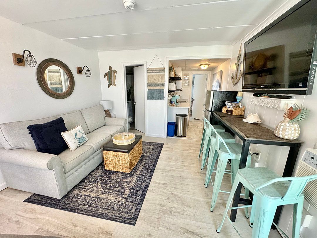 A living room with a couch, table, chairs, and a flat-screen tv