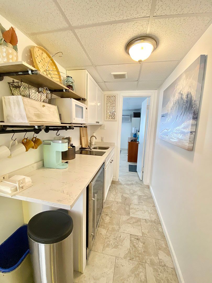 A kitchen with a sink, microwave, and trash can.