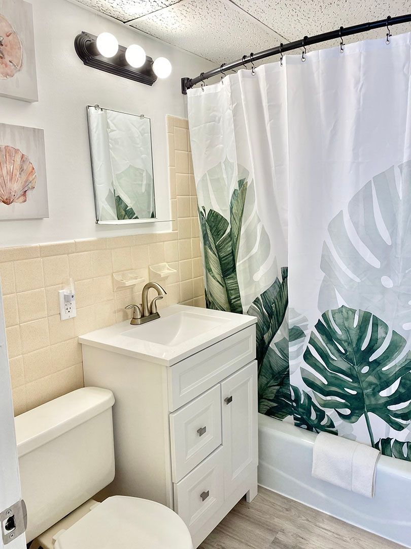 A bathroom with a toilet, sink, mirror, and shower curtain.