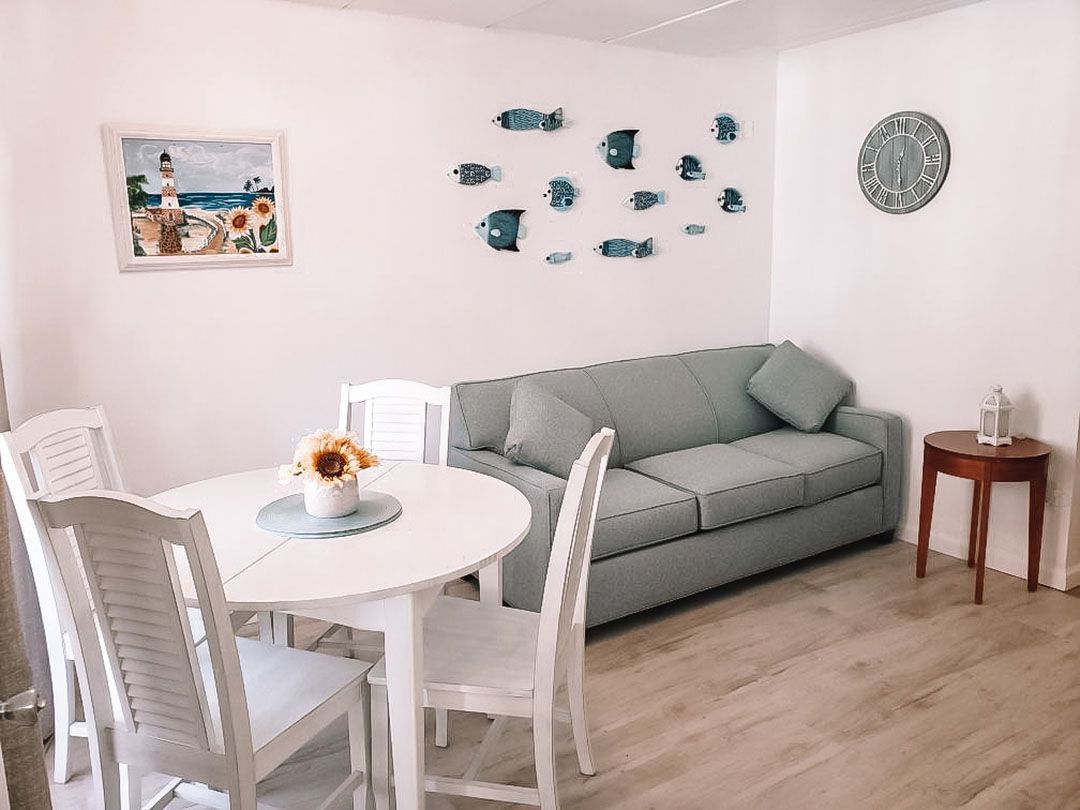 A living room with a couch, table, chairs, and a painting on the wall.