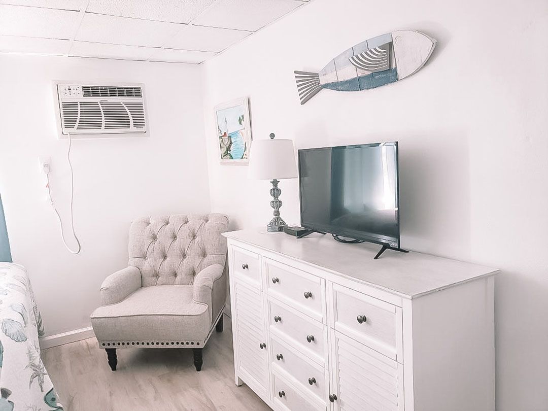 A living room with a chair, dresser, and television.