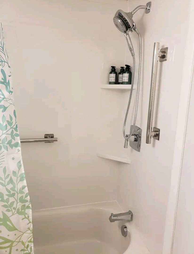 A bathroom with a tub, shower, and bottles on a shelf.