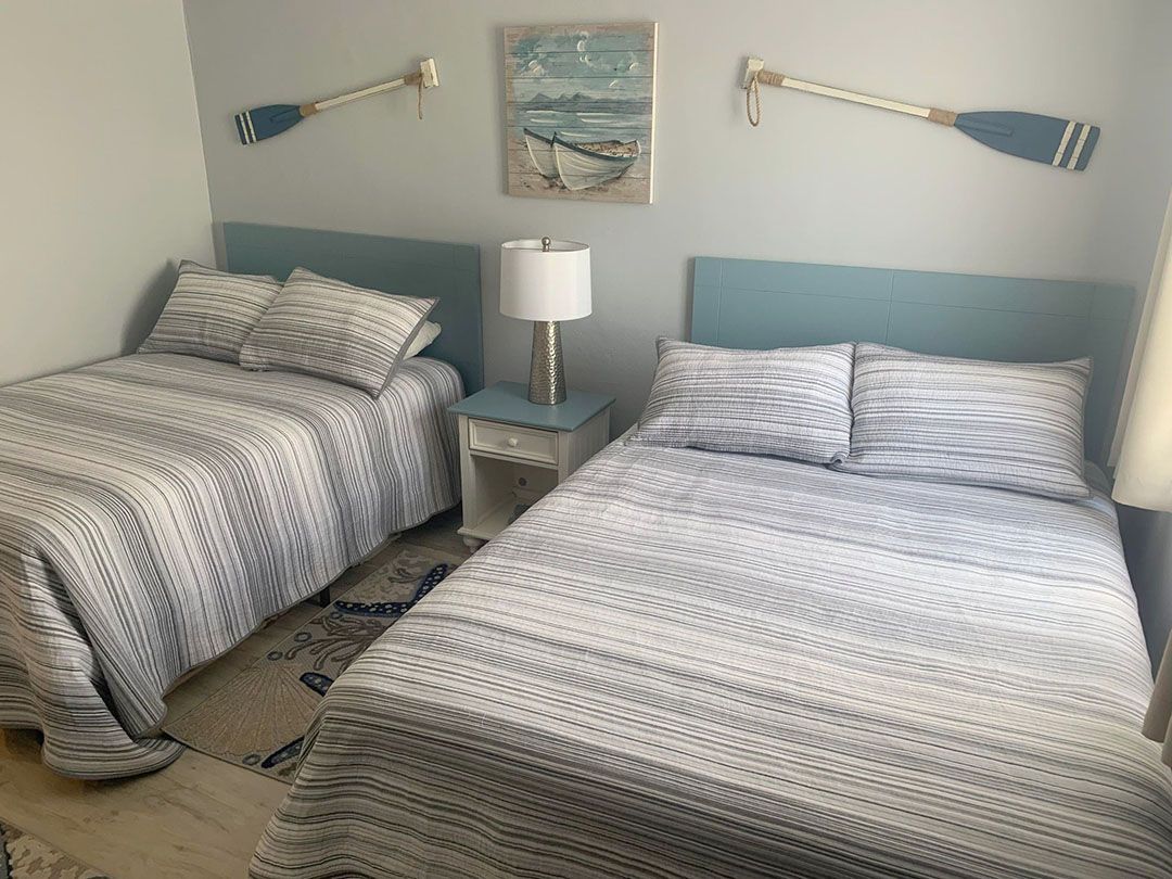 A bedroom with two beds and a lamp