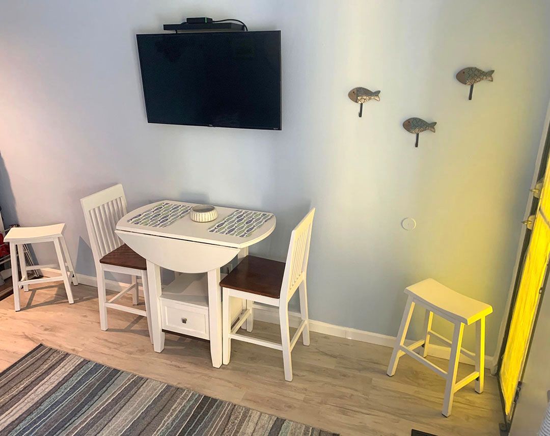 A small dining room with a table and chairs and a flat screen tv.
