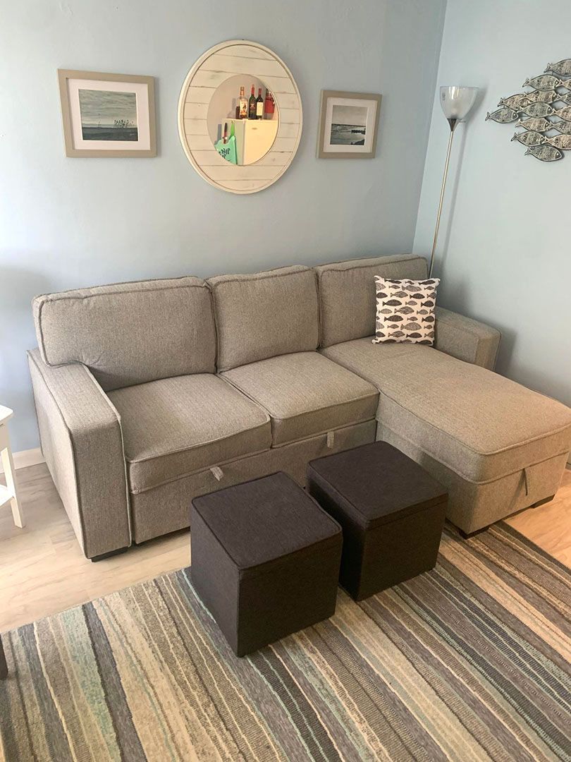 A living room with a sectional couch and two ottomans