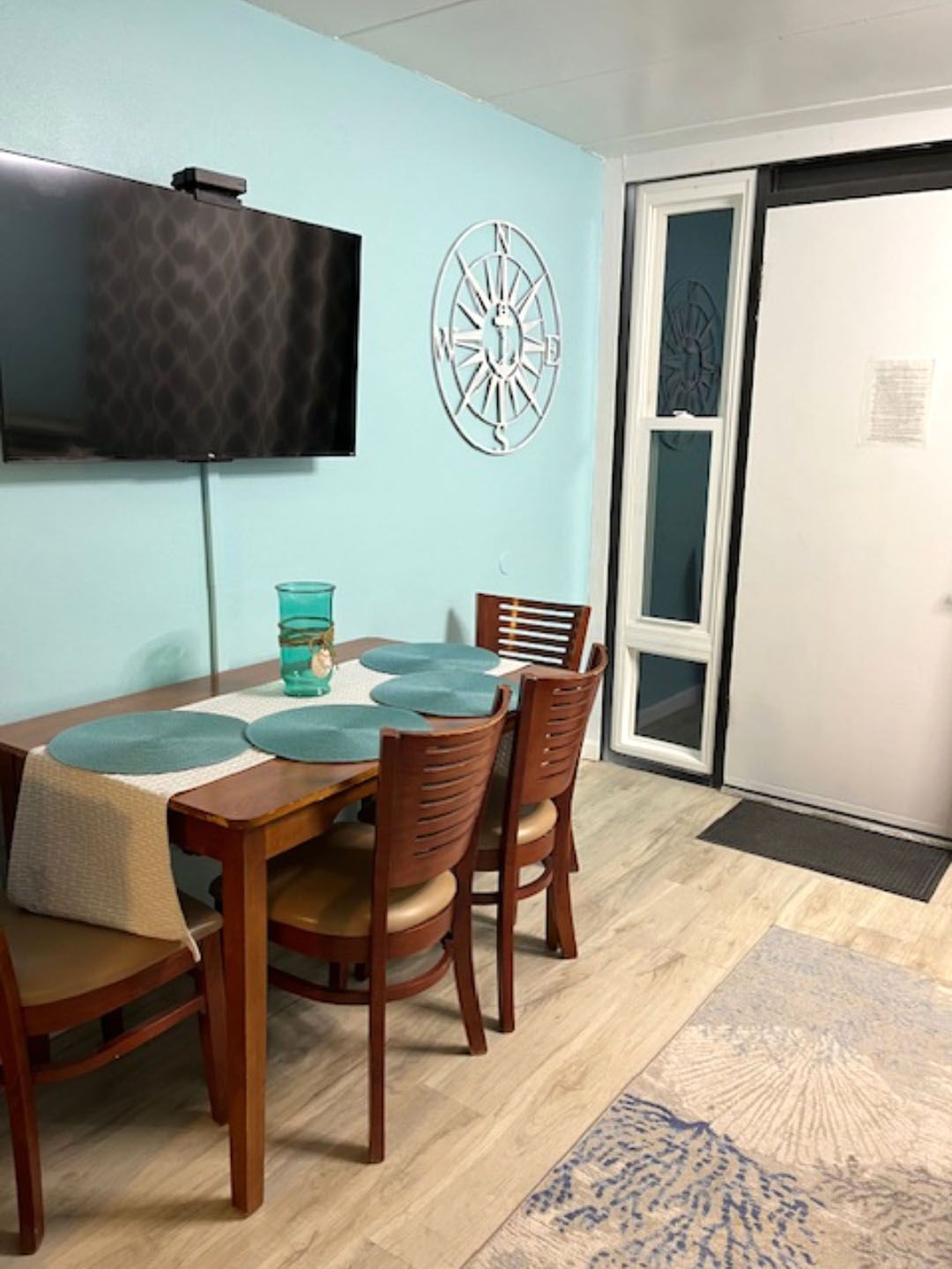 A dining room with a table and chairs and a flat screen tv.