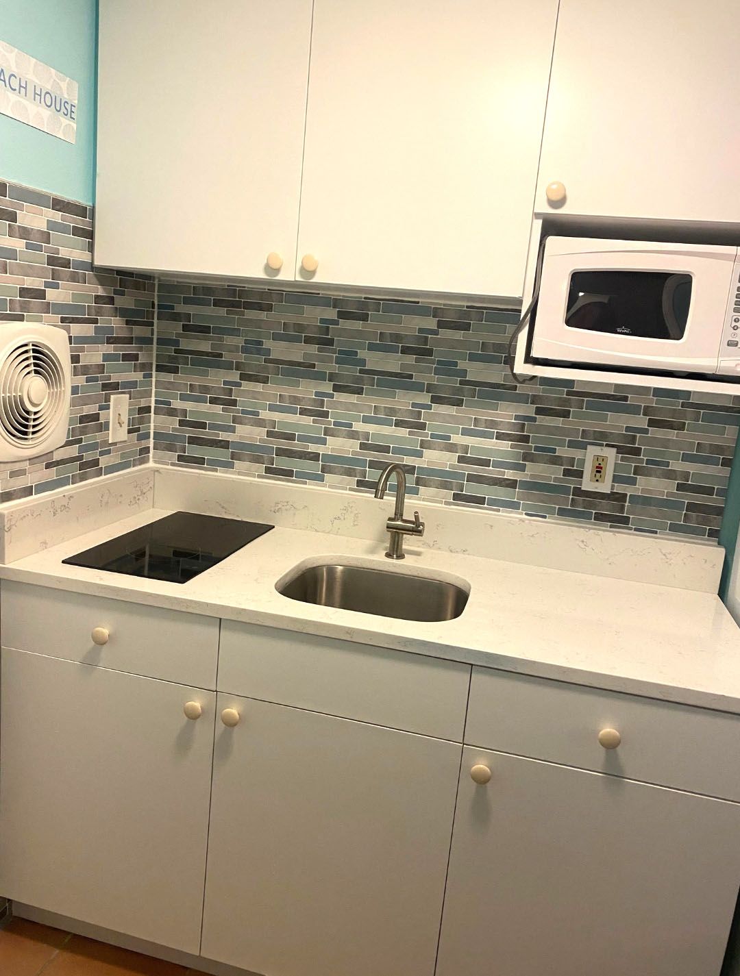 A kitchen with a sink, stove, and microwave.