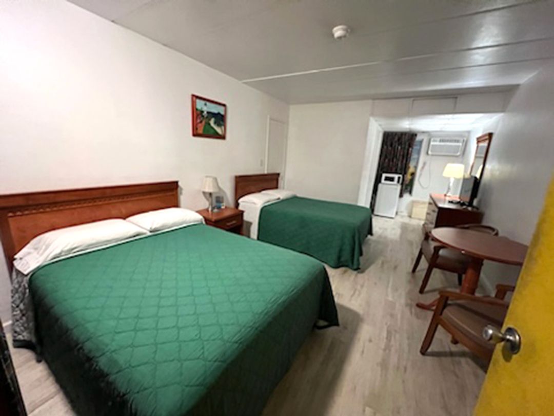 A hotel room with two beds, a table, and chairs