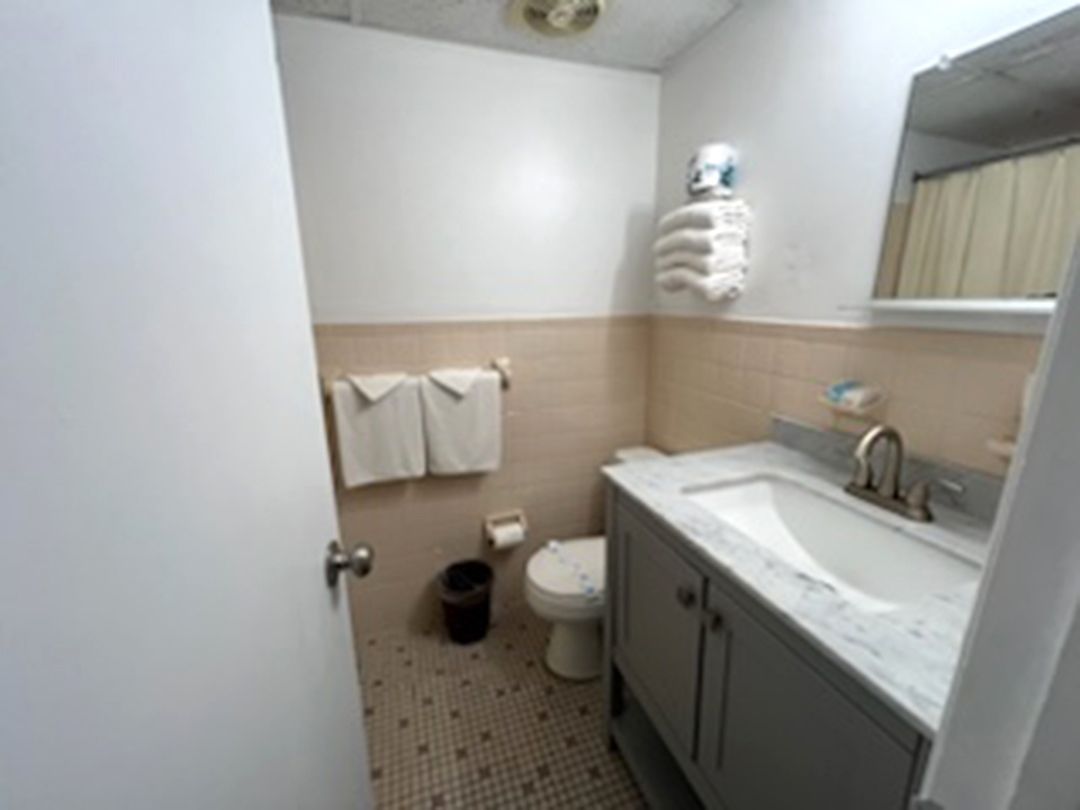 A bathroom with a toilet, sink, and mirror