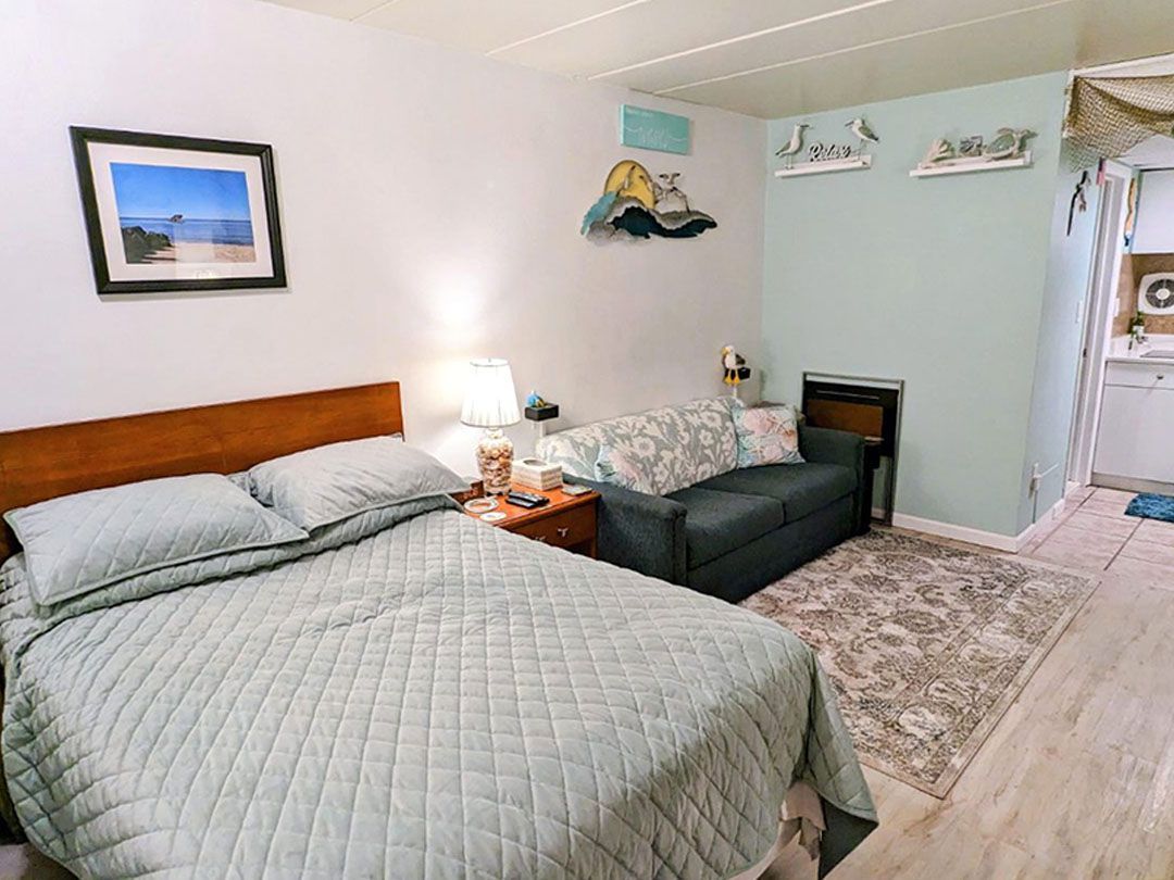 A bedroom with a bed, couch, and picture on the wall