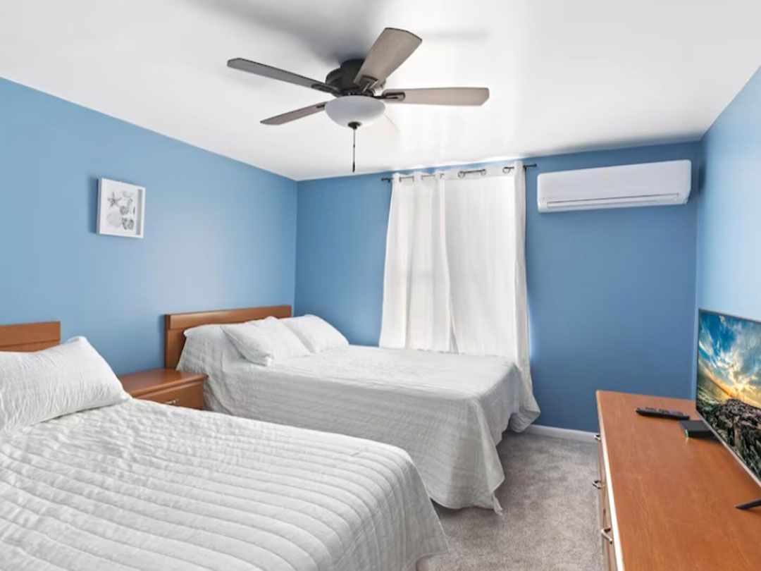 A bedroom with two beds and a ceiling fan